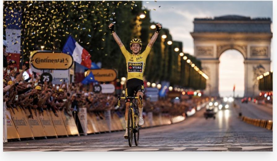 Winnaar in de gele trui met geheven armen op de Champs-Élysées bij de Arc de Triomphe